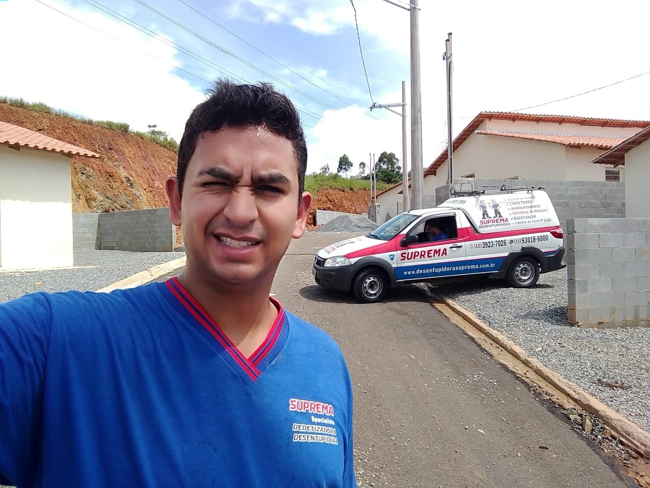 Profissional da Suprema Desentupidora uniformizado ao lado do veículo da empresa durante atendimento de limpeza de caixa de gordura
